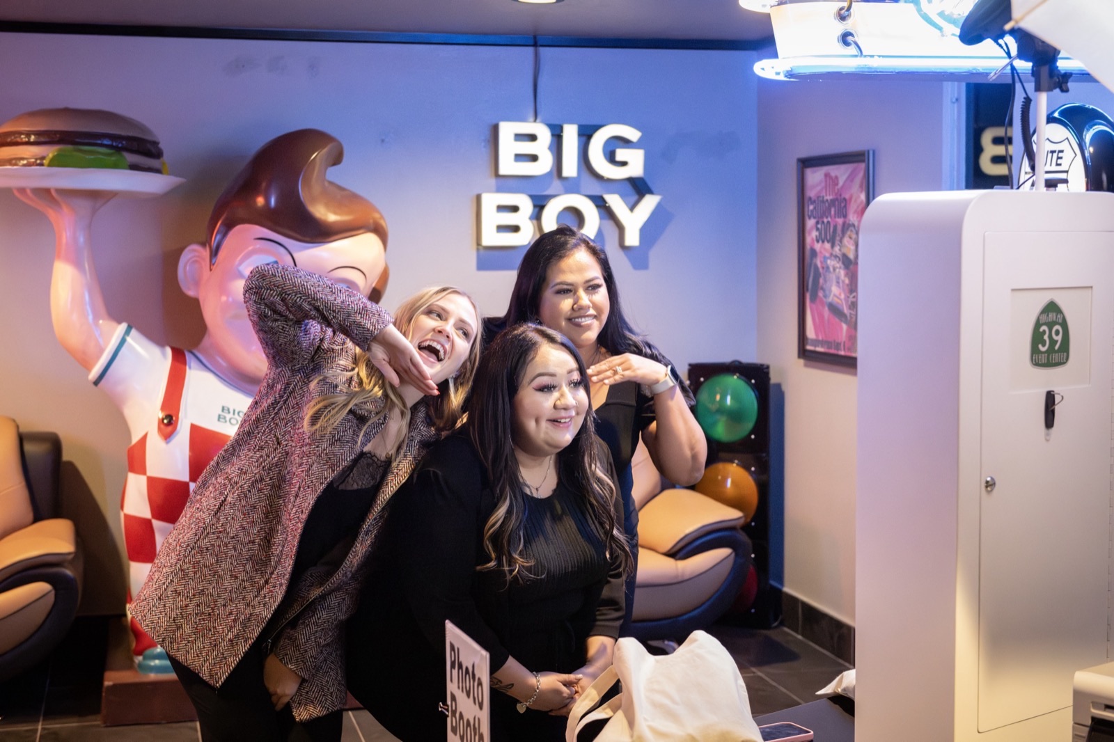 Friends laughing together at Big Boy photo booth during party at Highway 39 Event Center